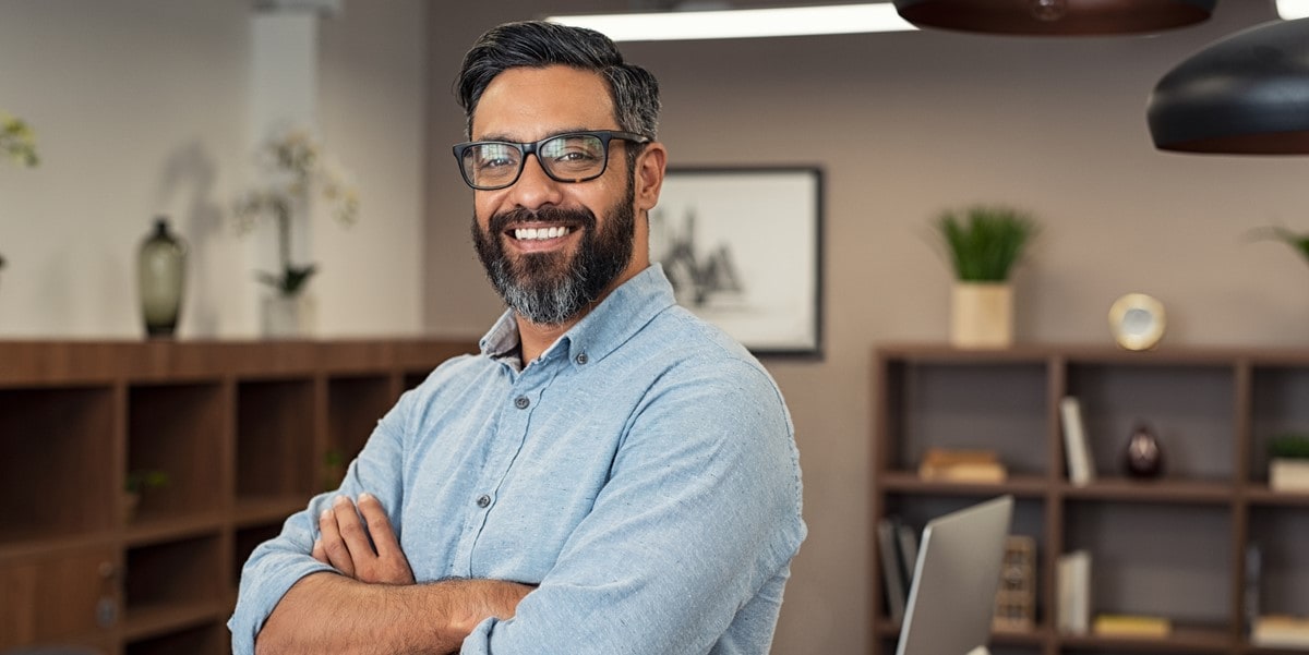 man smiling with arms crossed in office setting
