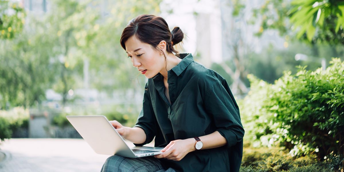 woman using laptop sitting outdoors