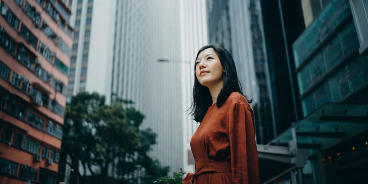 woman standing outside in city, buildings behind her