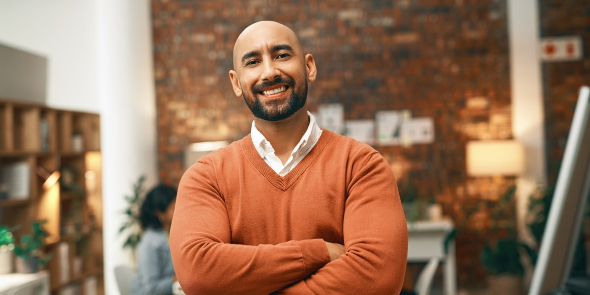 man smiling with arms crossed, in the office