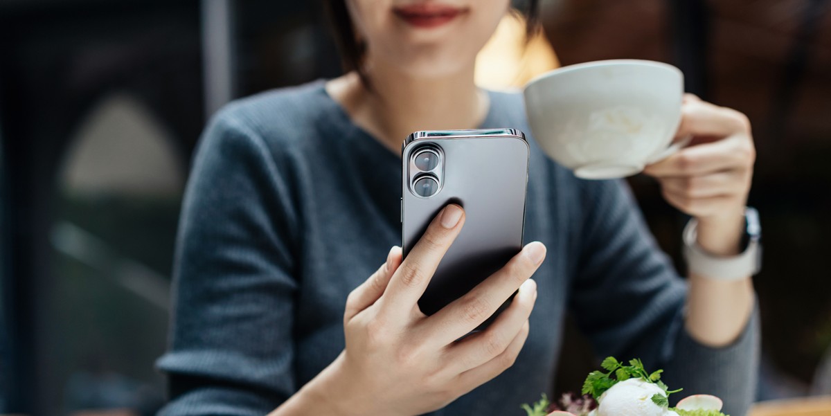 woman drinking coffee and using cellphone at a restaurant