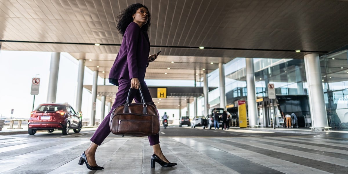 professional woman walking into airport with bag