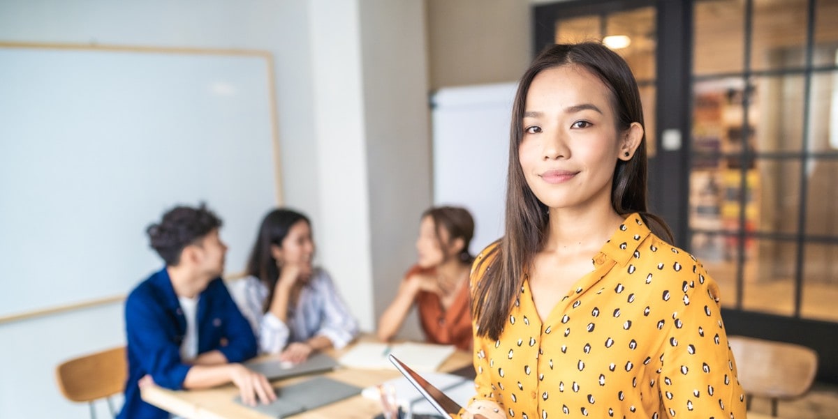professional woman in the office, colleagues in the background meeting a table
