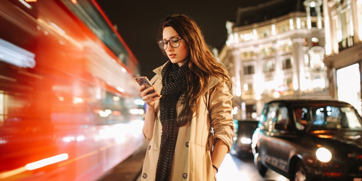 woman standing outside in city, building and cars in background