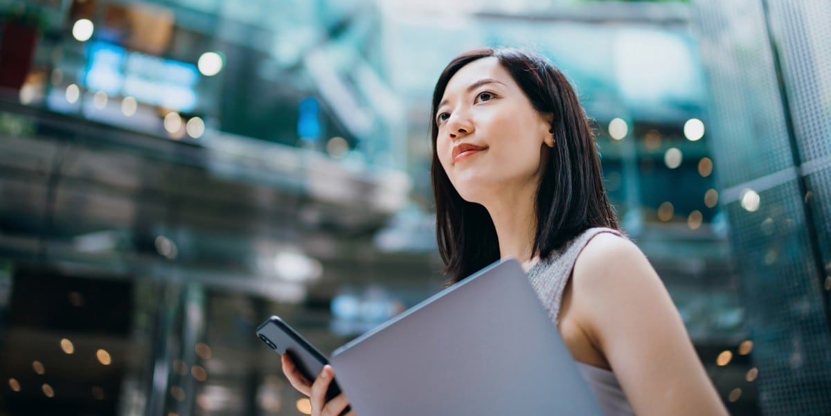 woman holding laptop and cellphone