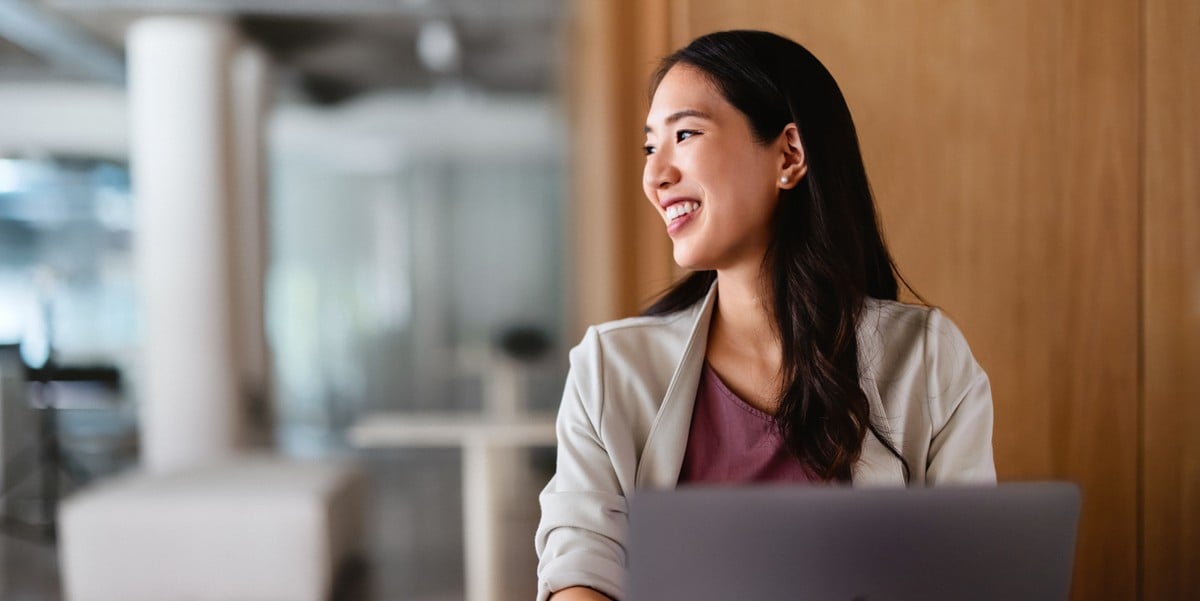 businesswoman in the office smiling, laptop in front of her