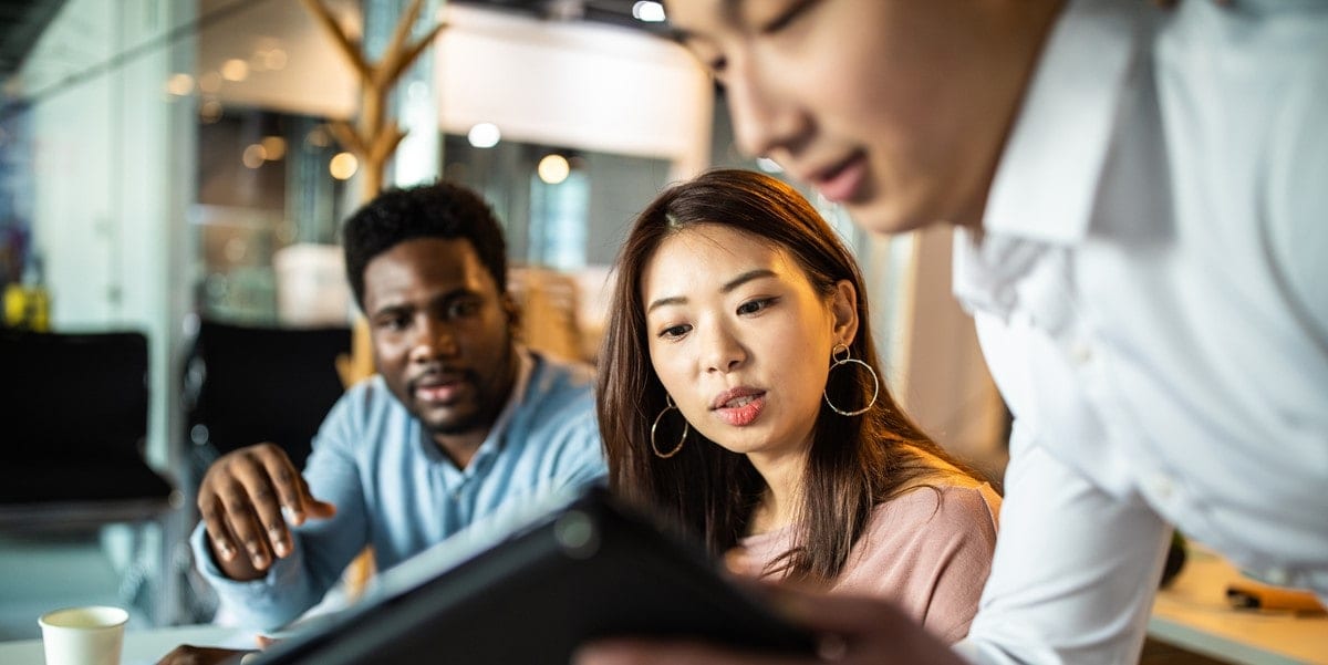3 people in office looking at a tablet
