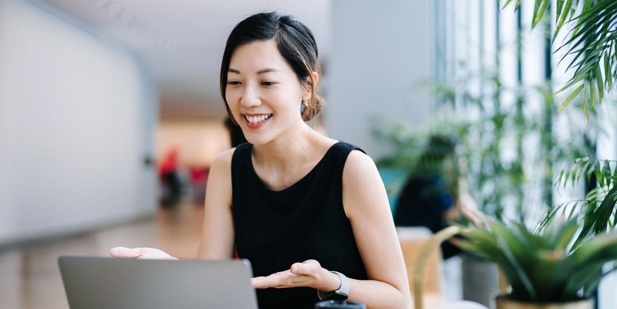 woman smiling, working on a laptop at the office