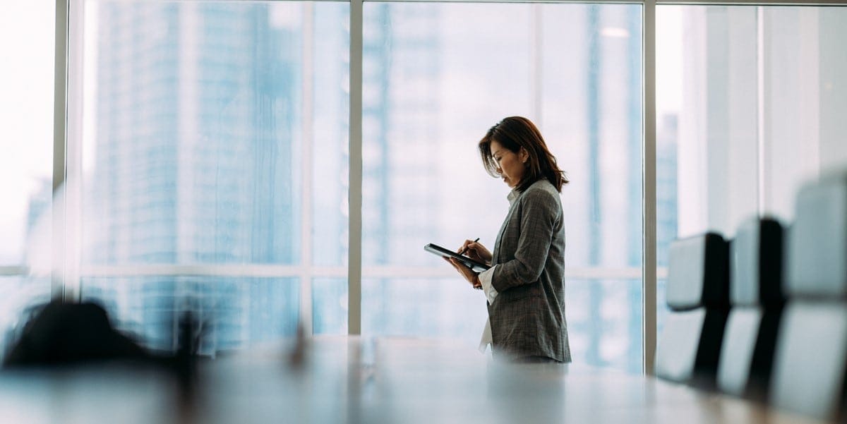 woman in office conference room looking down at phone