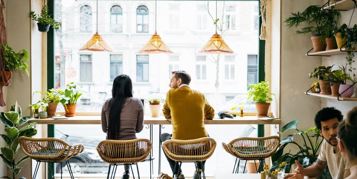 two people sitting on stools at a restaurant bar
