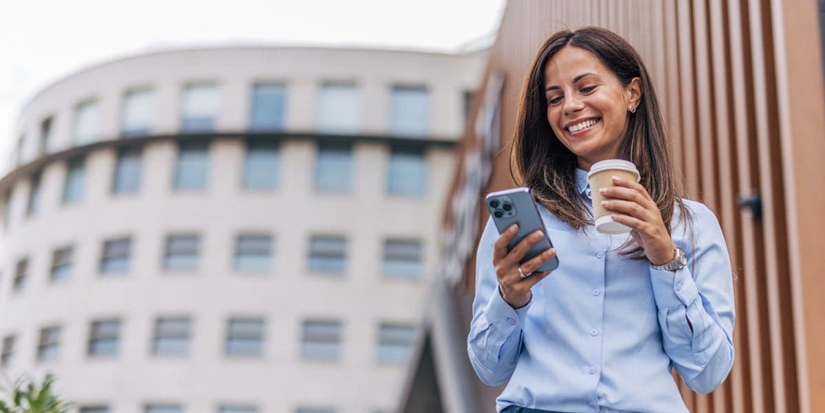 woman smiling holding coffee cup and cell phone
