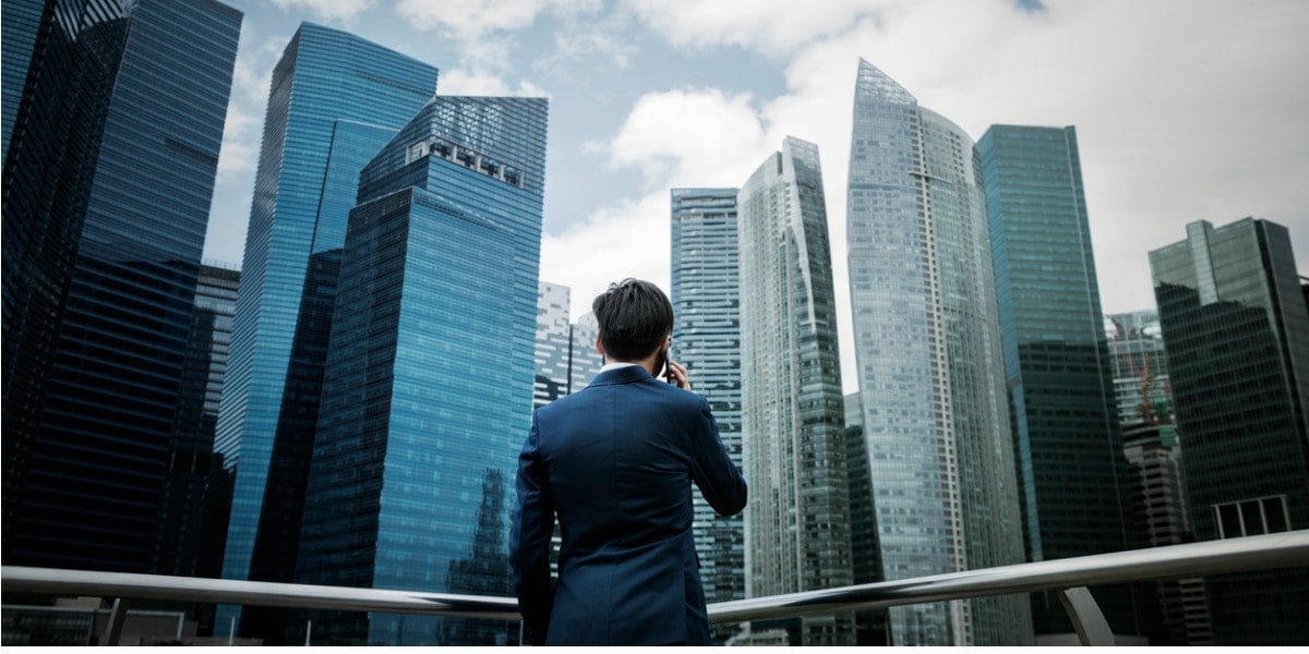 man standing facing skyscraper building