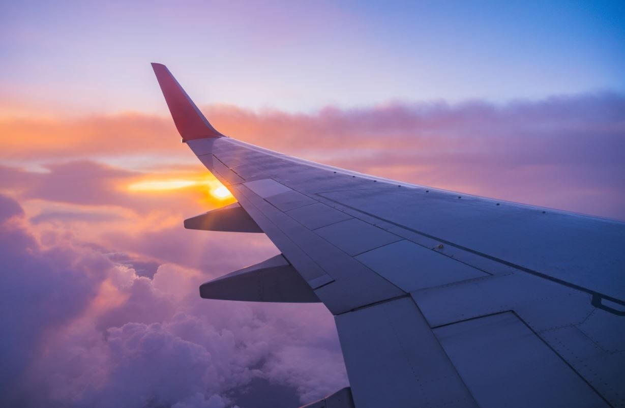 airplane wing with clouds and sunset in the background