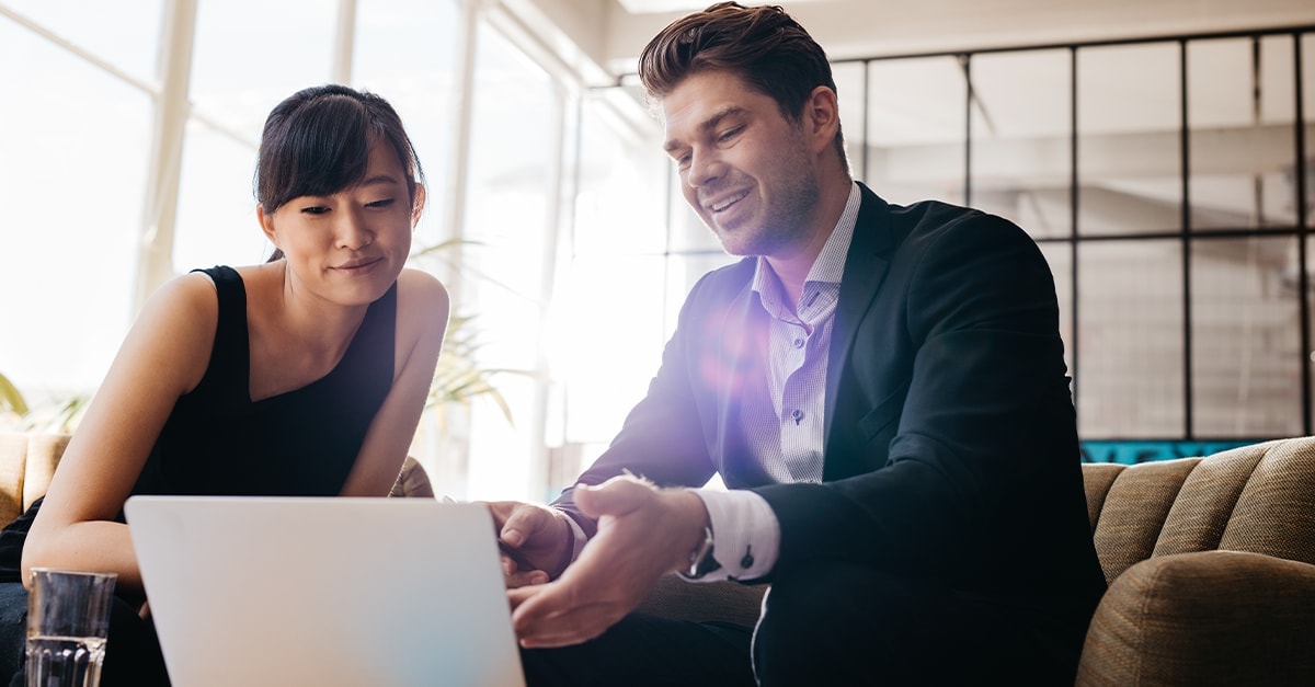 a woman and a man sitting looking at a laptop together