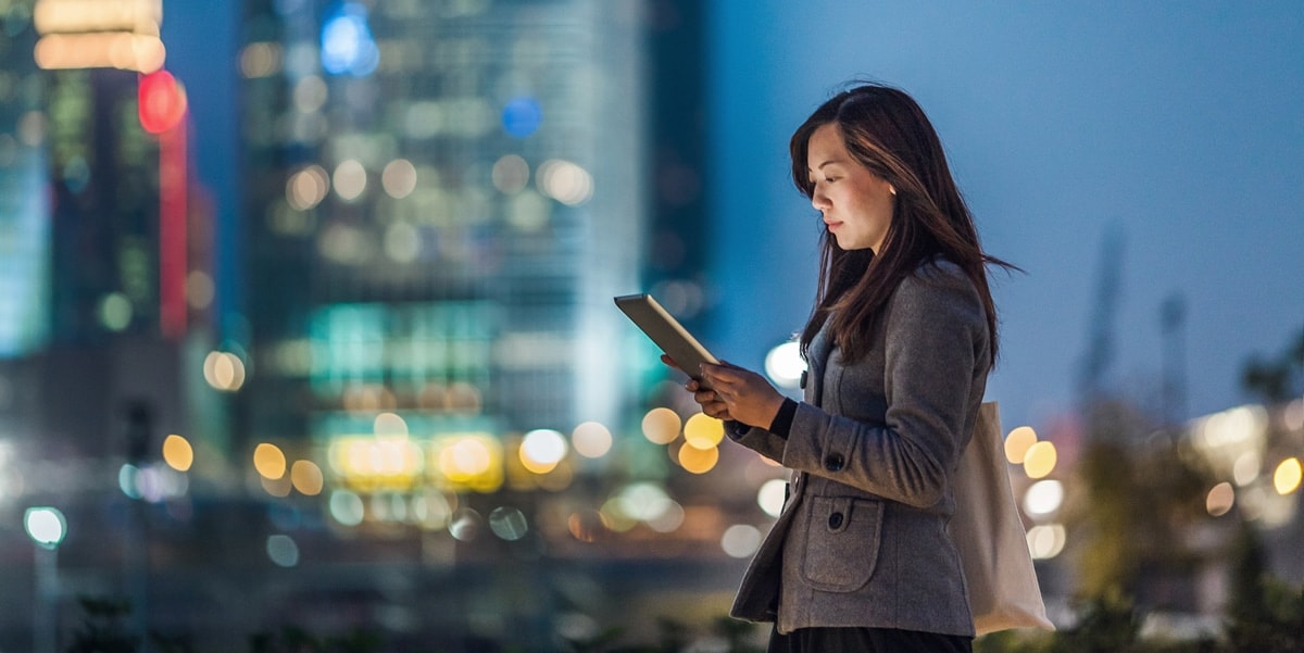 Woman standing outside looking at her phone, buildings