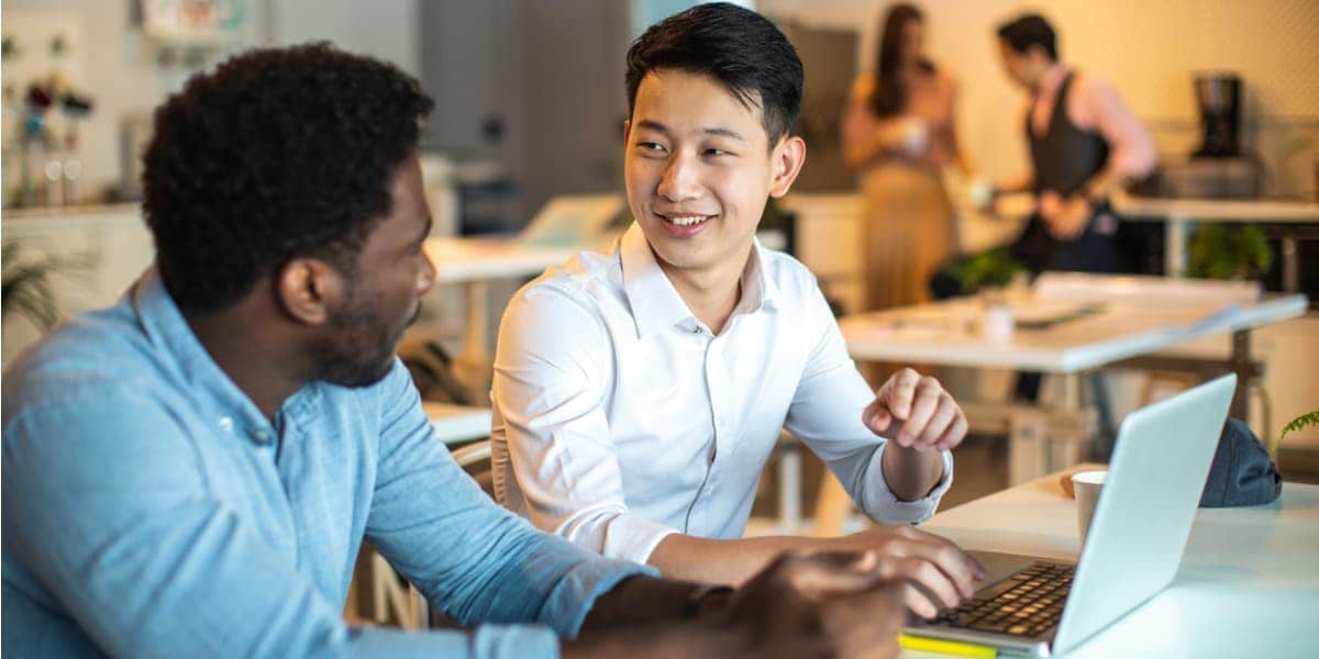 two coworkers having a discussion with a laptop between them