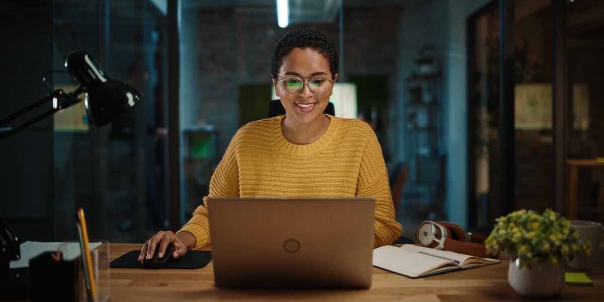 woman sitting and smiling looking at a laptop
