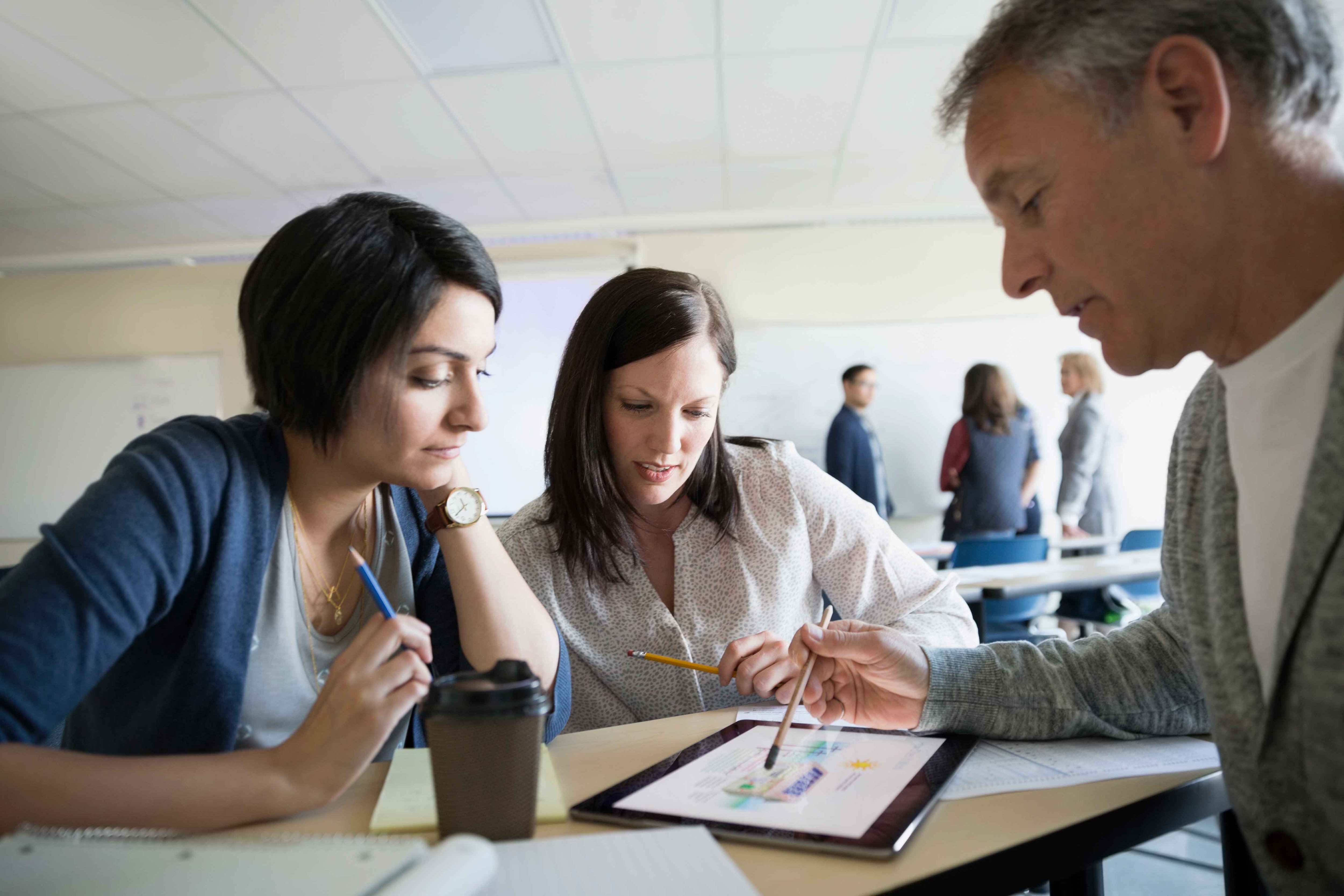 three business people sitting down looking at a tablet