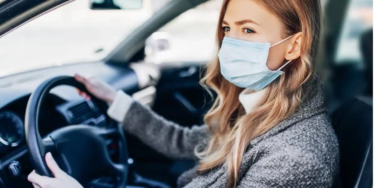 young girl in mask sitting in a car