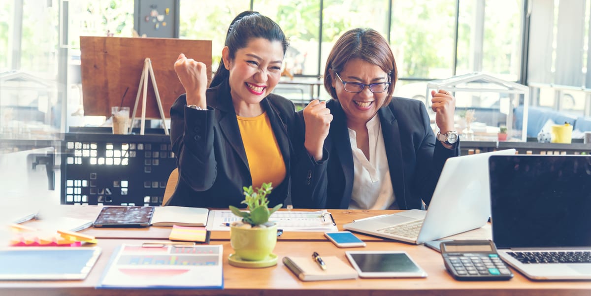 two women at a computer, cheering excitedly