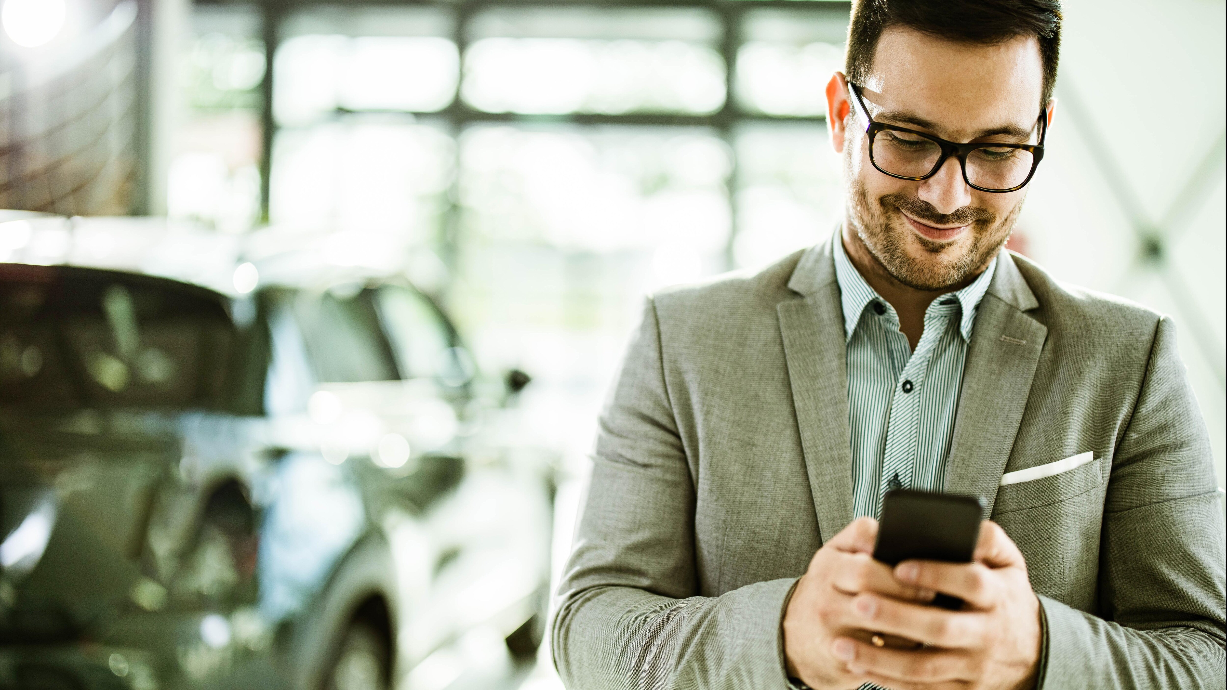 person looking at phone with car in the background