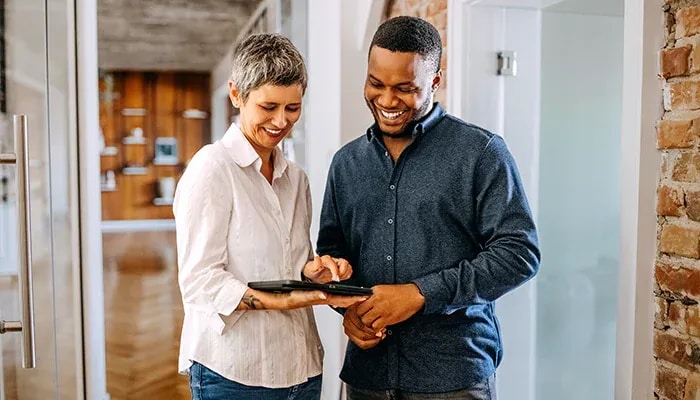 man and woman discussing work on tablet