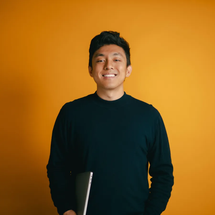 Man smiling and standing against orange background
