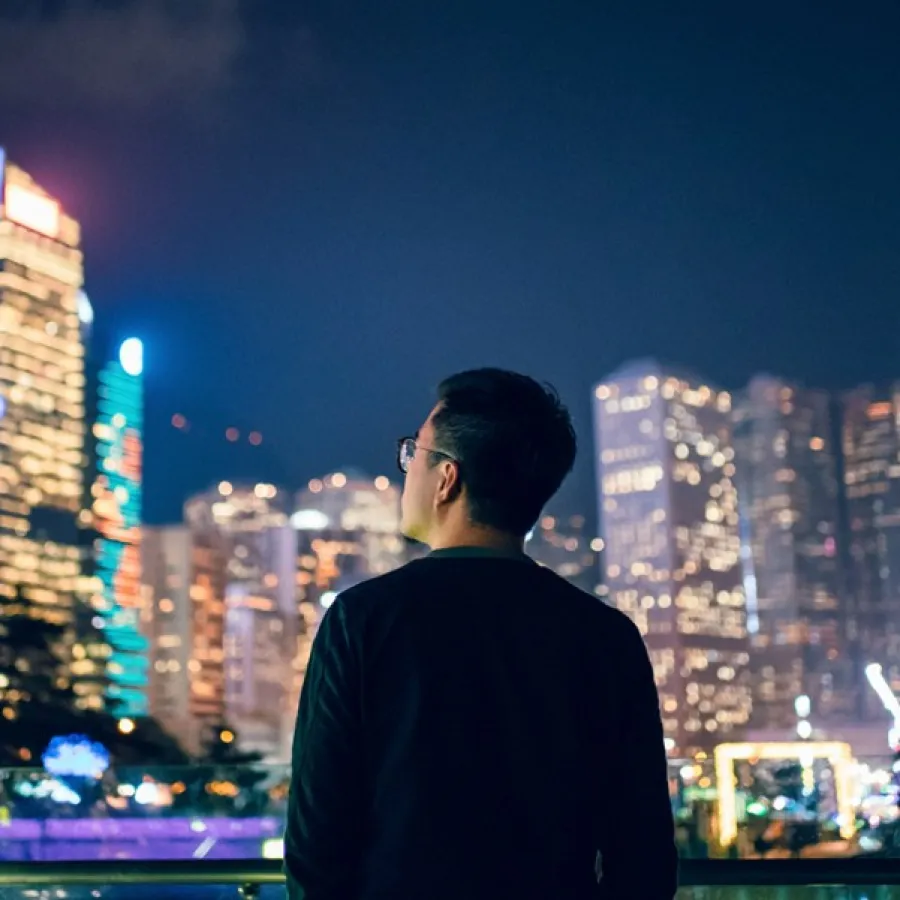 man looking out toward city skyline at night