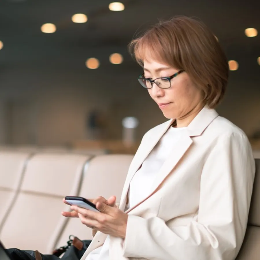 traveler sitting in airport lounge using cellphone and laptop