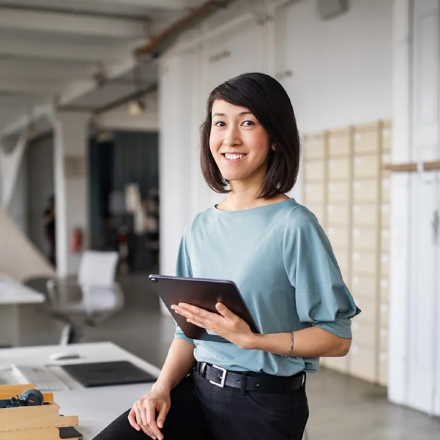 woman standing in office, holding a tablet
