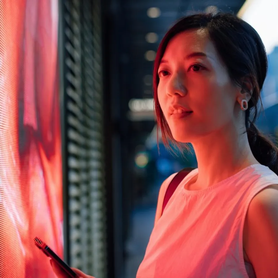 woman standing on train platform, holding cell phone