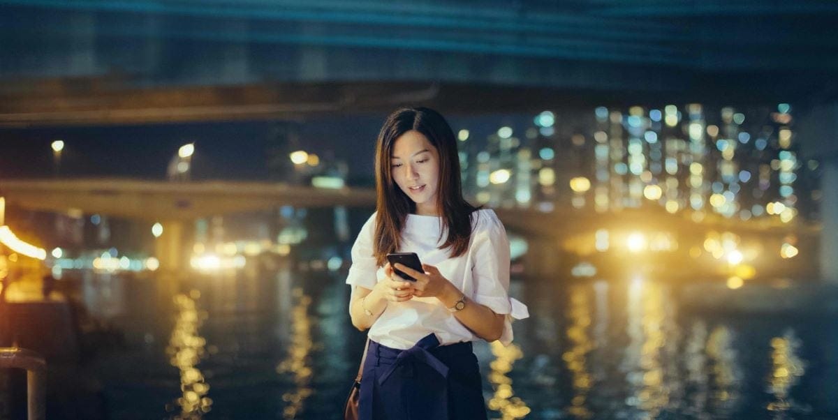 woman outside at night looking at her phone