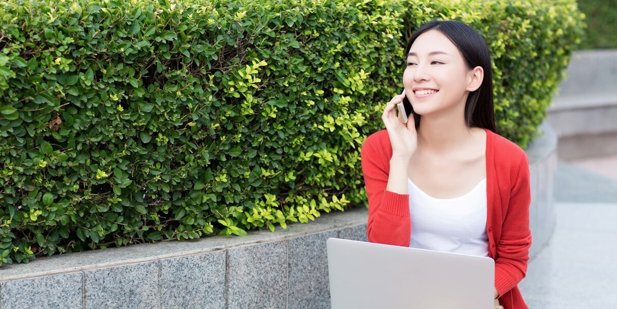 woman outside on the phone with laptop