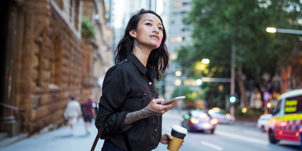 woman standing outside waiting for ride, phone in hand